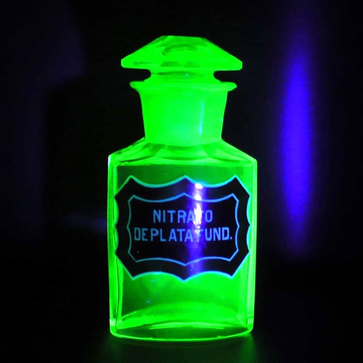 Uranium glass apothecary bottle glowing under uv light.