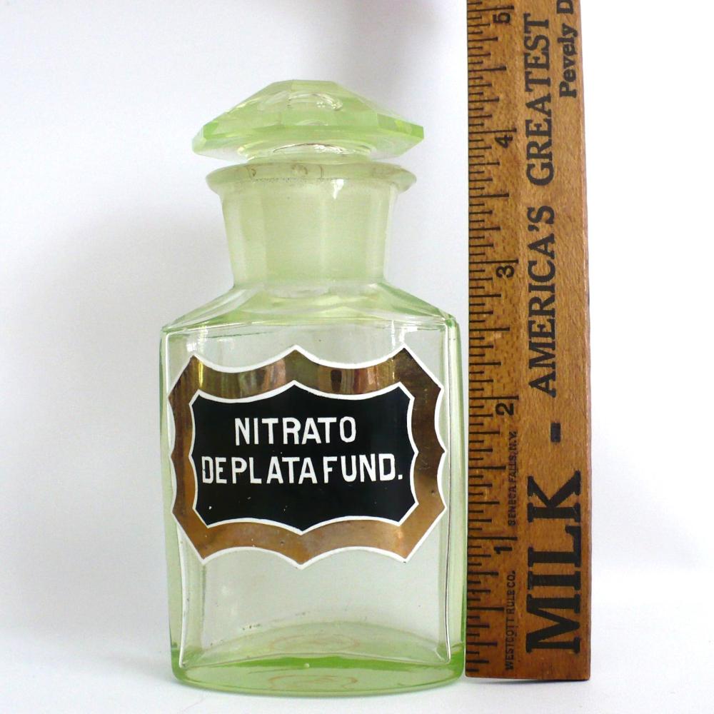 Uranium glass apothecary bottle under regular light next to ruler showing height