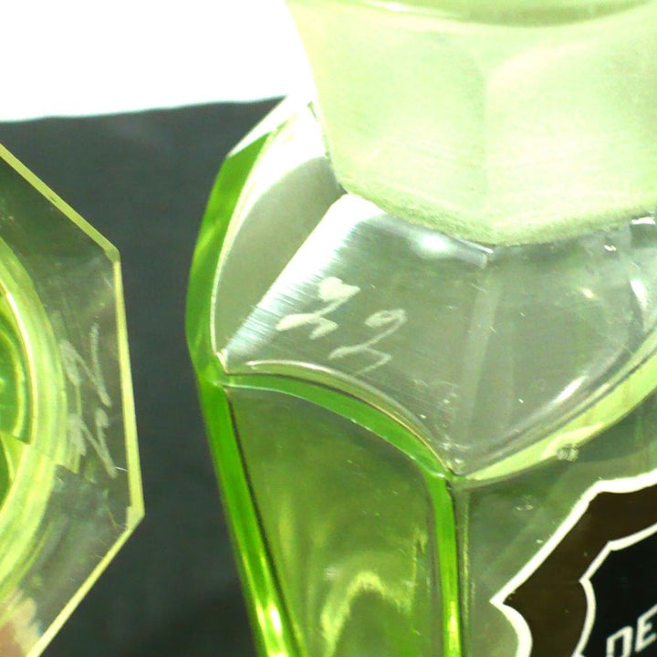 Uranium glass apothecary bottle under regular light showing bottle and lid with matching number etchings.