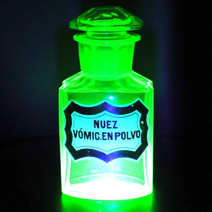 Uranium glass apothecary bottle glowing under uv light.