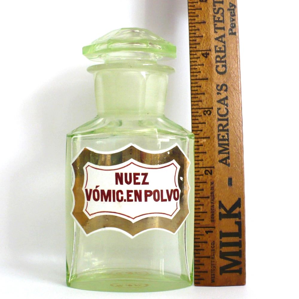 Uranium glass apothecary bottle under regular light next to ruler.