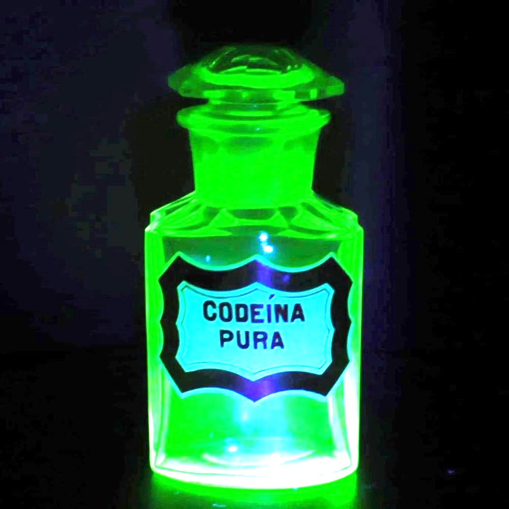 Uranium glass apothecary bottle glowing under uv light.